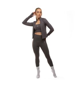 Woman in dark athletic wear striking a pose in a clean studio setting.